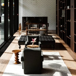 Moderne Lounge im Roomers Baden-Baden mit großen Fensterfronten und gemütlicher Sitzlandschaft.