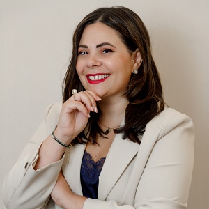 Romana Perfetti, lächelnde Speakerin im Business-Outfit – Portrait vor hellem Hintergrund